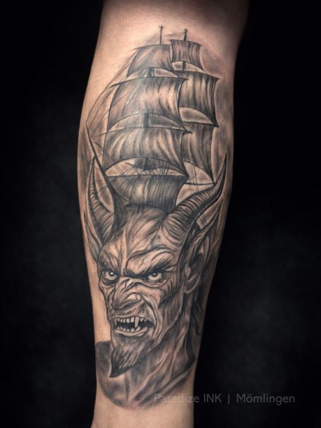 Tattoo eines geflügelten Wesens mit einem Schiff im Hintergrund.