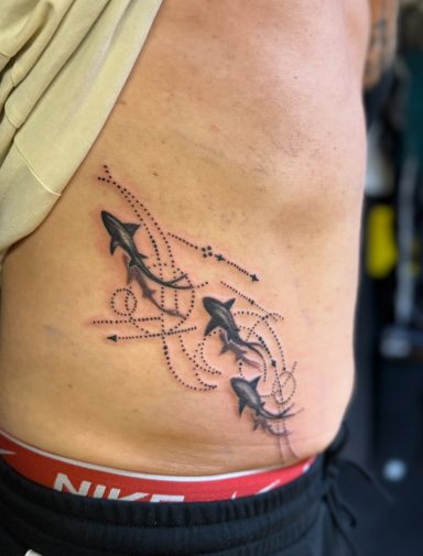 Tattoo auf der Seite mit stilisierten Sternen und geschwungenen Linien.