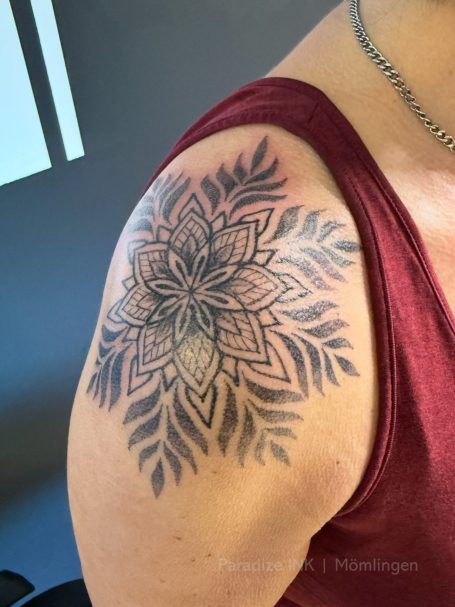 Mandala-Tattoo auf dem Oberarm mit floralen und geometrischen Mustern.