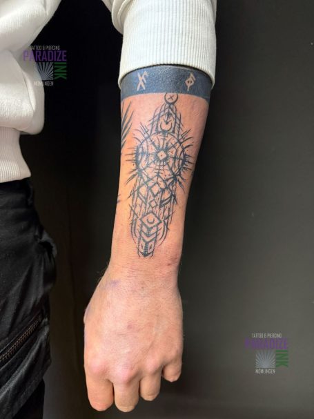 Tattoo eines stilisierten Designs mit geometrischen Mustern auf einem Unterarm.
