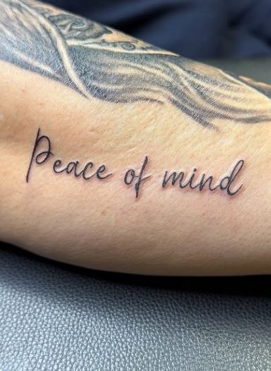 Tattoo auf dem Unterarm mit der Schrift "Peace of mind".
