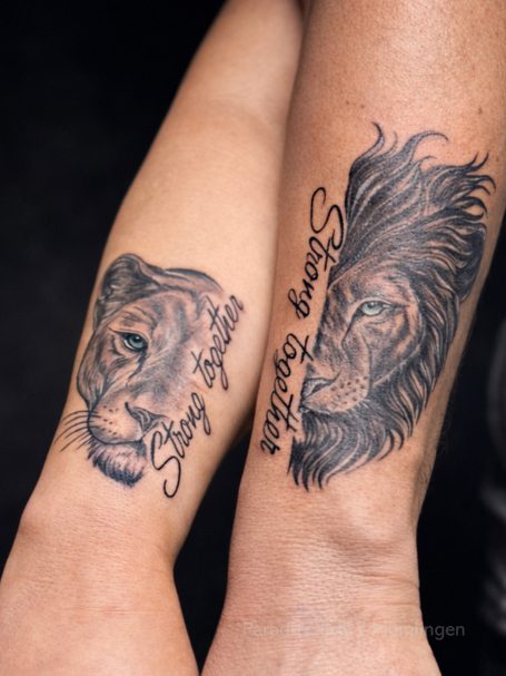 Tattoo von einem Löwenkopf auf zwei Unterarmen, kunstvoll und detailliert.