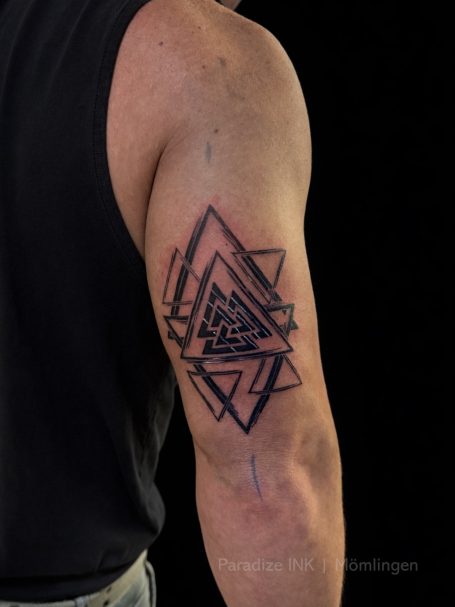 Schlichte geometrische Tattoo-Designs in Schwarz auf dem Oberarm eines Mannes.
