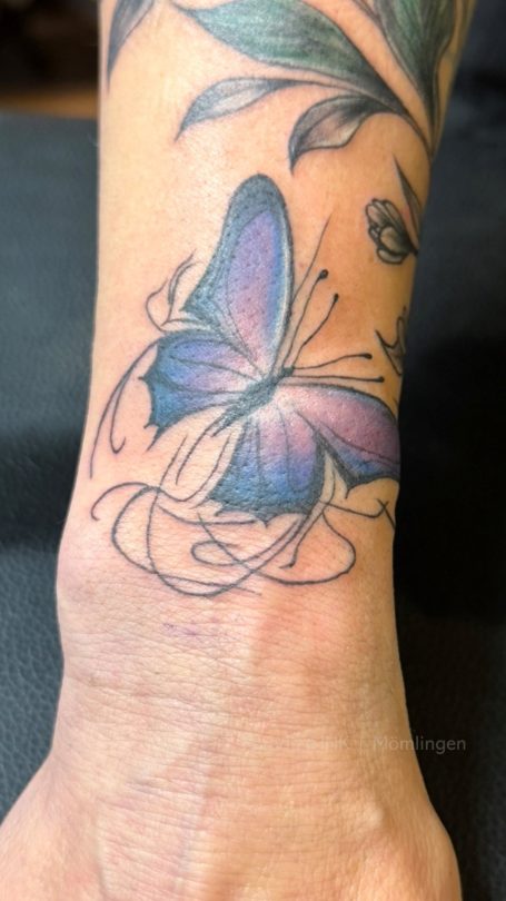 Bunte Schmetterling-Tätowierung auf dem Handgelenk.