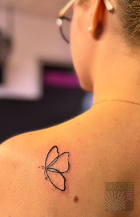 Schmetterling-Tattoo auf der Schulter einer Person.