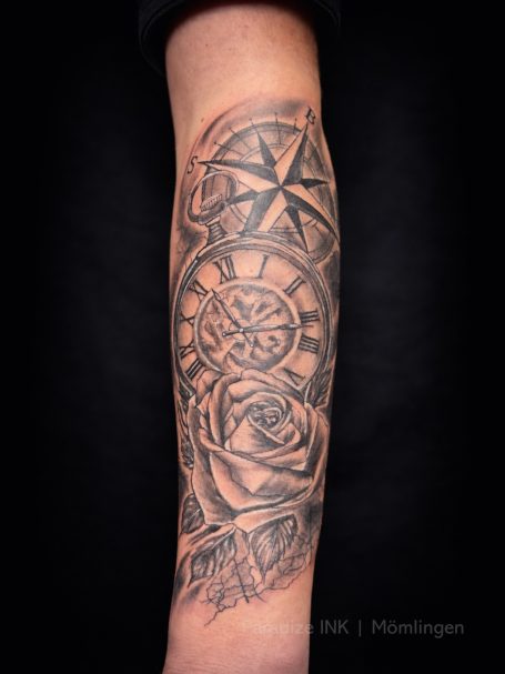 Tattoo auf einem Unterarm mit Kompass, Rosen und geometrischen Mustern.