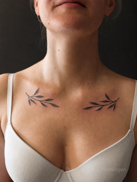 Tattoo Paradize INK Mömlingen Blaue Blätter-Tätowierungen auf der Haut des Schlüsselbeins. Paradize INK Mömlingen