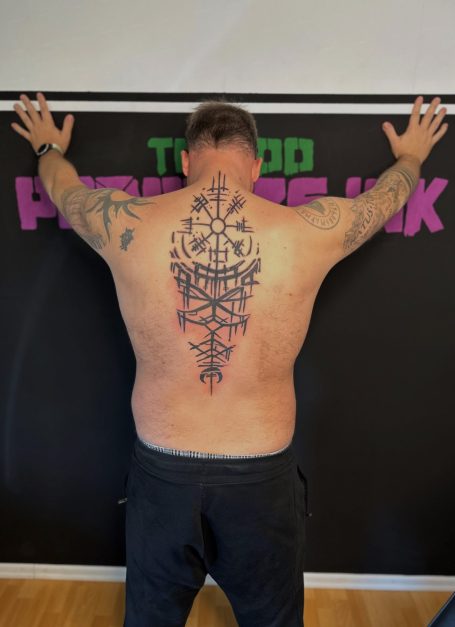 Rücken eines Mannes mit großem, detailliertem Tattoos in Schwarz.